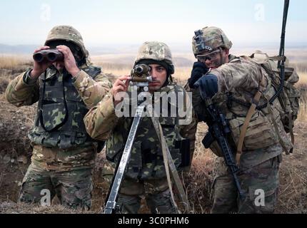5 décembre 2018 - zone d'entraînement de Vaziani, Géorgie - le sergent Sanchez de l'armée américaine affecté au peloton rouge, compagnie Cobra, 2e bataillon, 8e régiment de cavalerie, 1re équipe de combat de brigade blindée, 1re division de cavalerie et des soldats géorgiens examinent le champ de tir lors d'une opération de tir réel d'armes combinées d'une compagnie multinationale à l'appui du programme de préparation de défense de Géorgie à la zone d'entraînement de Vaziani en Géorgie, Dec. 5, 2018. Le GDRP est un programme conjoint dans lequel l'armée américaine conseille, encadre et forme le personnel et les commandants géorgiens afin d'améliorer la préparation au combat. (Crédit image : © U.S. Army/ZUMA Wire/ZUM Banque D'Images