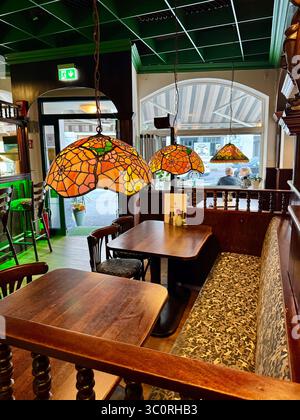 Intérieur confortable d'un restaurant traditionnel à Lübeck, en Allemagne, avec un éclairage chaleureux avec des lampes suspendues en vitraux, des meubles en bois et une vue sur O. Banque D'Images