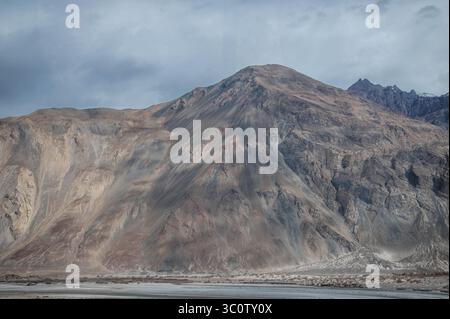 Paysage himalayen majestueux avec des pics arides, une végétation de contreforts et la trajectoire asséchée de la rivière Shyok dans le Ladakh, en Inde. Banque D'Images