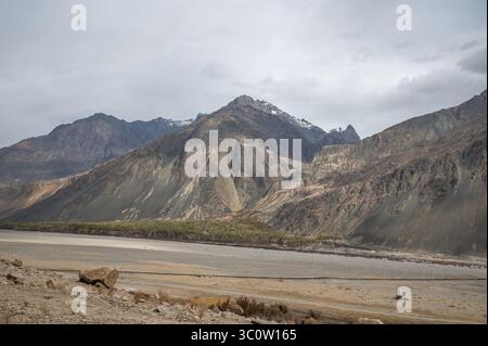 Paysage himalayen majestueux avec des pics arides, une végétation de contreforts et la trajectoire asséchée de la rivière Shyok dans le Ladakh, en Inde. Banque D'Images