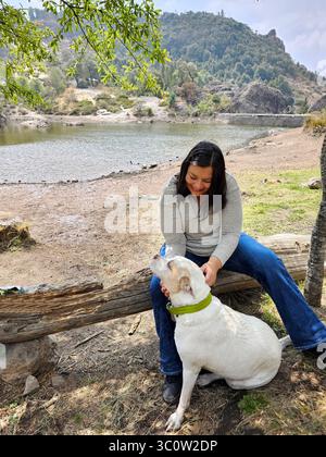 Une femme adulte latina passe du temps à l'extérieur avec son chien de soutien émotionnel comme thérapie pour le stress et l'anxiété Banque D'Images