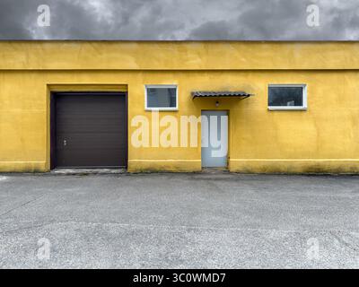 porte de porte métallique fermée du garage de service ou de l'entrepôt. ancien bâtiment industriel avec murs en stuc jaune. vue de face. Banque D'Images