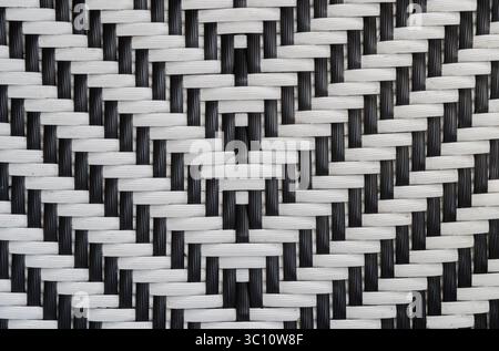 Motif de tissage abstrait bicolore noir et blanc sur mobilier d'extérieur en rotin/osier en plastique. Concept d'arrière-plan. Banque D'Images