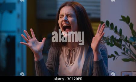 Femme ennuyée folle fille caucasienne en colère criant fort à la maison femme célibataire criant stress émotionnel folle criant furieux expression Banque D'Images