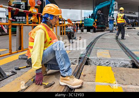 Travailleurs chinois réparant la ligne de tramway pendant que le service est en fonctionnement, North point, Hong Kong, SAR, Chine Banque D'Images