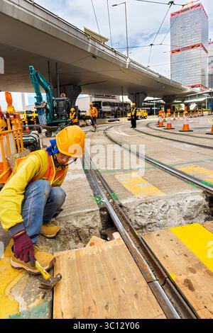 Travailleurs chinois réparant la ligne de tramway pendant que le service est en fonctionnement, North point, Hong Kong, SAR, Chine Banque D'Images