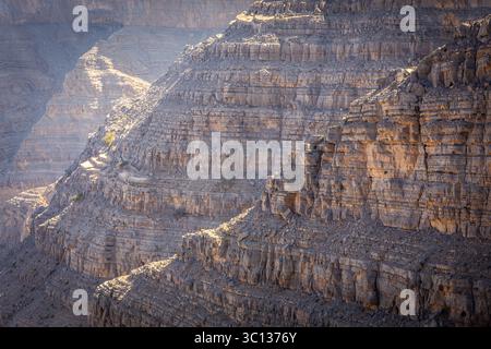 Formations rocheuses et couches rocheuses et strates avec des crêtes éclairées par le soleil, vue rapprochée de la pente de montagne du désert fissurée, sèche et rocheuse aux Émirats arabes Unis. Banque D'Images