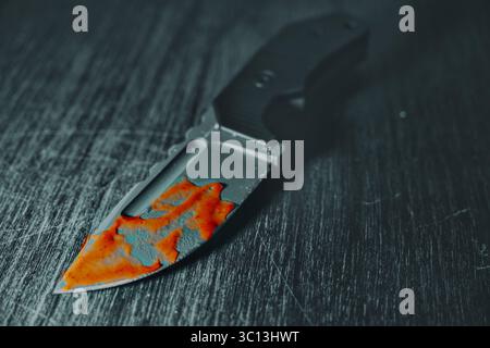 Couteau sanglant sur la table en bois, gros plan. Photo en noir et blanc avec du sang rouge vif. Seule la lame est visible. Concept dramatique pour crime, thriller ou Banque D'Images