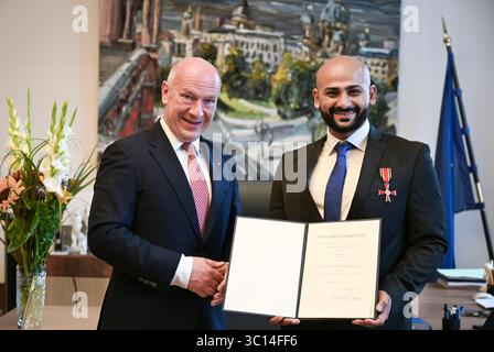 Berlin, Allemagne. 22 juillet 2025. Kai Wegner (CDU), maire de Berlin, remet la Croix fédérale du mérite à Yousef Ayoub, travailleur social. Ayoub organise des matchs de football conjoints avec les enfants et la police dans les écoles, les jeunes et les institutions sociales du quartier Soldiner Kiez de Berlin-Wedding. Crédit : Jens Kalaene/dpa/Alamy Live News Banque D'Images