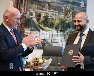 Berlin, Allemagne. 22 juillet 2025. Kai Wegner (CDU), maire de Berlin, remet la Croix fédérale du mérite à Yousef Ayoub, travailleur social. Ayoub organise des matchs de football conjoints avec les enfants et la police dans les écoles, les jeunes et les institutions sociales du quartier Soldiner Kiez de Berlin-Wedding. Crédit : Jens Kalaene/dpa/Alamy Live News Banque D'Images