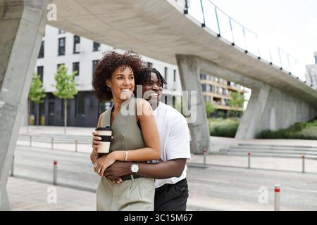 Un jeune couple à la mode partage un moment joyeux tout en explorant la ville par une chaude journée d'été. Banque D'Images
