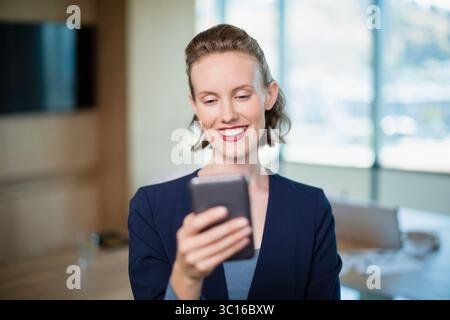 Smartphone assis sur une table en bois dans la salle de réunion, avec écran mural et papiers éparpillés Banque D'Images
