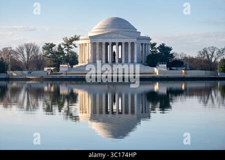 Jefferson Memorial reflété dans le bassin de Tidal Basin Washington DC // WASHINGTON DC — le côté nord du Jefferson Memorial se reflète dans les eaux calmes du bassin de Tidal Basin au petit matin. Le mémorial néoclassique, inauguré en 1943, rend hommage à Thomas Jefferson, troisième président des États-Unis et auteur principal de la Déclaration d'indépendance. La structure circulaire présente une statue en bronze de Jefferson entourée d'extraits de ses écrits sculptés dans les murs intérieurs. Le Tidal Basin, une entrée artificielle reliée au fleuve Potomac, a été créé à la fin des années 1800 Banque D'Images