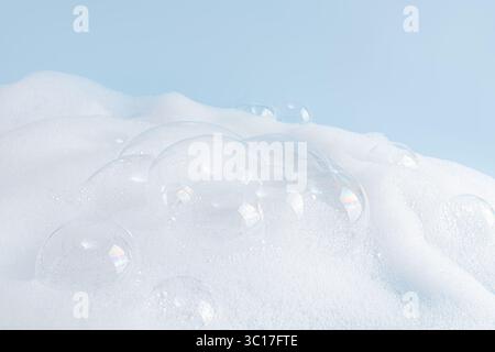 Mousse moelleuse blanche chic, texture de mousse de savon avec des bulles claires sur fond bleu. Un espace de copie. Mise en page pour la publicité détergent, cosmétiques spa Banque D'Images