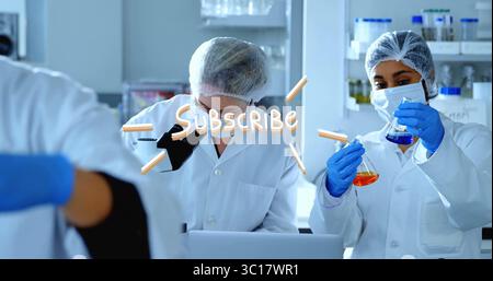 Techniciens de laboratoire en blouse inspectant des échantillons au microscope et pipettant des liquides bleus et oranges en laboratoire Banque D'Images