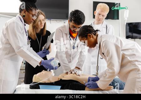 Professionnels de santé effectuant une formation à la RCP sur un mannequin réaliste dans un hôpital ou une clinique Banque D'Images