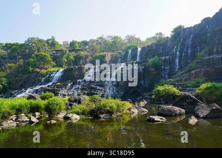 Une photo grand angle de la cascade de Pongour montre des cascades à plusieurs niveaux plongeant le long de falaises escarpées dans un bassin calme et réfléchissant en contrebas, au Vietnam Banque D'Images