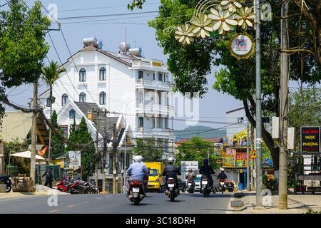 Da Lat, Vietnam- 24 mars 2025 : les motards roulent le long d'une rue animée de Da Lat, entourée de bâtiments, de panneaux et de câbles aériens enchevêtrés Banque D'Images