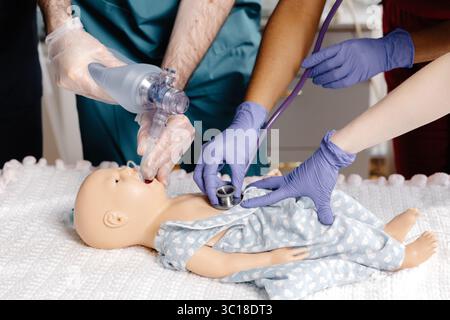 Groupe diversifié d'étudiants en médecine pratiquant l'intubation sur un mannequin de bébé, démontrant des compétences essentielles dans un environnement médical simulé Banque D'Images