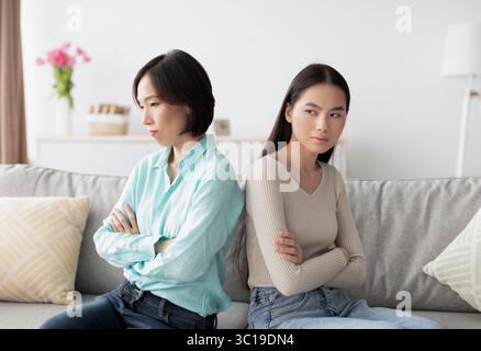 Elle a offensé la jeune femme asiatique et sa mère mature qui se sont assise dos à dos sur un canapé après discussion, se ignorant mutuellement Banque D'Images
