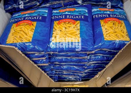 Fossano, Italie - 17 juillet 2025 : pâtes macaroni penne rigate dans des emballages bleus et transparents empilés dans une boîte en carton à vendre dans le magasin de rabais LIDL Banque D'Images