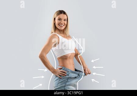Bonne dame blonde en Jean, montrant ample à la taille Banque D'Images