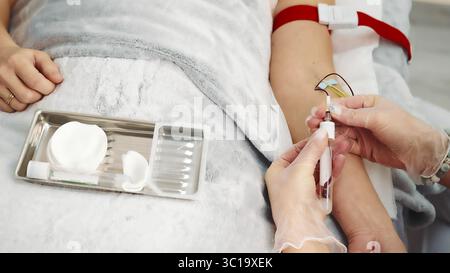 Procédure de prélèvement sanguin en milieu médical. Vue rapprochée d'un professionnel de la santé effectuant une procédure de prélèvement sanguin à l'aide d'une seringue et Banque D'Images