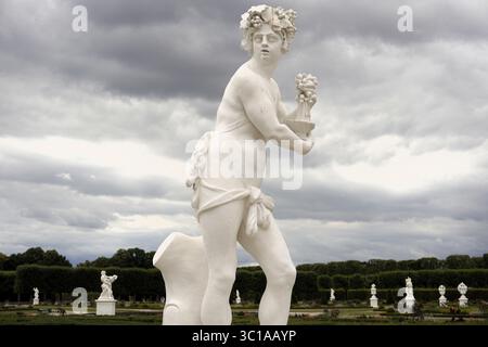 Statue baroque en grès de l'ancien Dieu grec Dionysos tenant des raisins et une coupe de vin dans le jardin de sculptures du palais Herrenhausen, à Hanovre Banque D'Images