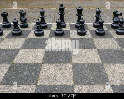 Jeu d'échecs en plein air avec des pièces noires sur tableau noir et blanc. Copyspace Banque D'Images