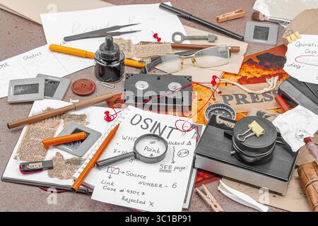 Espace de travail créatif sur le thème OSINT avec des outils vintage, des notes manuscrites et des éléments de presse sur une table grunge. Accessoires thématiques, pose à plat, gros plan Banque D'Images