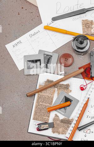 Espace de travail créatif sur le thème OSINT avec des outils vintage, des notes manuscrites et des éléments de presse sur une table grunge. Accessoires thématiques, plat, vue de dessus Banque D'Images