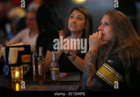 11 septembre 2014 - Minneapolis, MN, États-Unis - Un serveur au bar sportif industriel de Mac a marché devant un écran de télévision affichant Ray Rice et le commissaire de la NFL Roger Goodell avant le match Pittsburg Steelers vs Baltimore Ravens jeudi soir. - 11 septembre 2014, Minneapolis, Minn., Macs Industrial Sports Bar, un bar Ravens, les fans féminins regardant le football dans certains bars locaux. Que pensent-ils de la situation de Ray Rice ? (Crédit image : Carlos Gonzalez/Minneapolis Star Tribune/TNS via ZUMA Wire) Banque D'Images