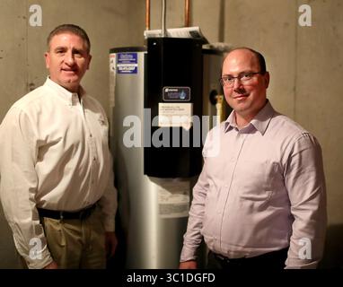 15 février 2018 - Lakeville, MN, États-Unis - Dave Reinke, de la Dakota Electric Association, et Jeff Haase, de Great River Energy, ont travaillé ensemble pour apporter une nouvelle technologie à une subdivision de Lakeville équipée de chauffe-eau intelligents qui ont réduit les coûts d'électricité de deux tiers. Ici, Dave Reinke, à gauche, et Jeff Haase sont photographiés à côté d'un chauffe-eau Steffe's Hydro plus, une unité de stockage thermique électrique alimentée par le réseau, qui se branche dans la technologie pour stocker l'énergie renouvelable. Et vu jeudi 15 février 2018, à Lakeville, MN....... La technologie permettra aux 81 nouvelles maisons d'un lotissement à Lakeville d'être Banque D'Images
