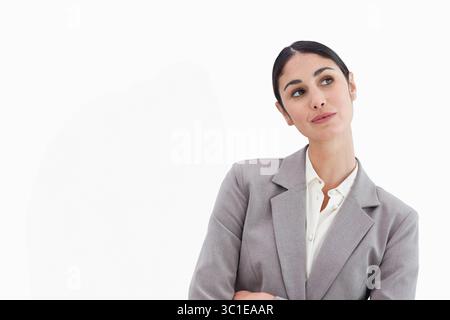 Femme portant blazer gris et blouse blanche debout avec les bras croisés regardant latéralement dans le studio Banque D'Images