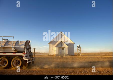 27 septembre 2011 - Minnesota, États-Unis - Un camion de transport de pétrole brut gronde sur un chemin de terre poussiéreux, devant l'ancienne église luthérienne Harland près de Watford City Dakota du Nord. Le boom pétrolier de Bakken a amené un nombre énorme de semi-camions dans la région, ce qui a mis le stress sur les routes de l'ouest du Dakota du Nord. (Crédit image : Glen Stubbe/Minneapolis Star Tribune/TNS via ZUMA Wire) Banque D'Images
