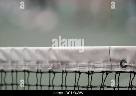 Gros plan d'un filet de tennis blanc sur un fond de court vert flou. Prise de vue détaillée pour les concepts sportifs, de compétition ou de loisirs avec espace de copie. Banque D'Images