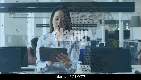 Chef de projet asiatique debout tenant une tablette dans un bureau ouvert, avec carte du monde et superposition de code Banque D'Images