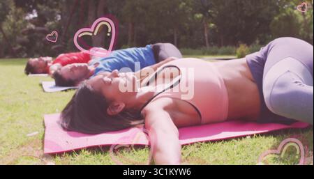 Femme couchée dans un soutien-gorge de sport, leggings étirant les bras sur la pelouse gazonnée du parc, avec des tapis de yoga Banque D'Images