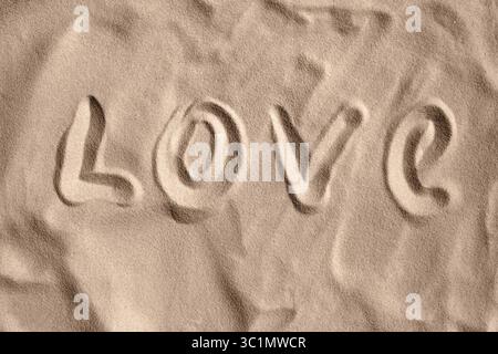 Le mot 'AMOUR' écrit avec Un doigt sur le sable de plage. Summer Love Vibe. Vue de dessus. Sunny Beach et écrit à la main 'LOVE'. Banque D'Images
