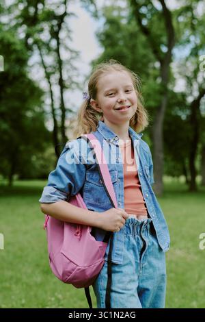 Portrait de fille caucasienne souriant à l'extérieur avec sac à dos dans le cadre du parc Banque D'Images