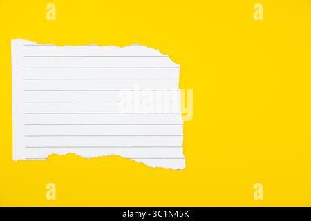 Papier de carnet ligné déchiré horizontal sur fond jaune vif pour une utilisation à l'école ou au bureau Banque D'Images