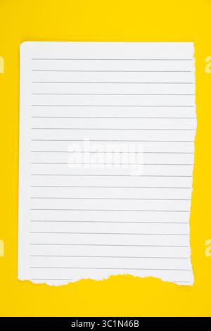 Papier ligné blanc déchiré en bas sur fond jaune vif pour la prise de notes, l'écriture, ou à des fins éducatives Banque D'Images