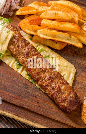 Kebab Adana traditionnel avec frites, lavash, boulgour et salade d'oignons Banque D'Images