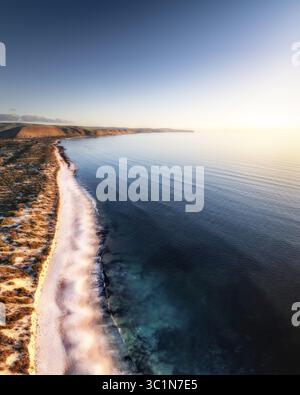 Vue aérienne de l'endroit où le sable doré rencontre les eaux turquoises, avec une lumière douce et éthérée baignant le littoral dans une lueur tranquille, Normanville, Australie méridionale, Australie. Banque D'Images