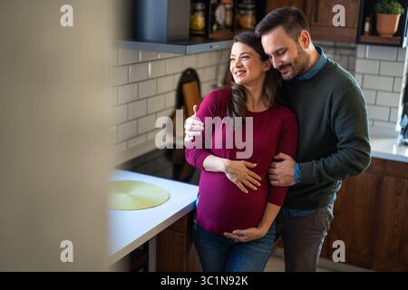 Homme amoureux embrasse sa femme enceinte, ils attendent ensemble l'arrivée du bébé. Amour, famille Banque D'Images