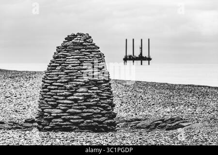 Un cairn en forme de ruche fait de pierres empilées sur une plage de galets, mêlant matériaux naturels et expression artistique sur la côte britannique. Banque D'Images