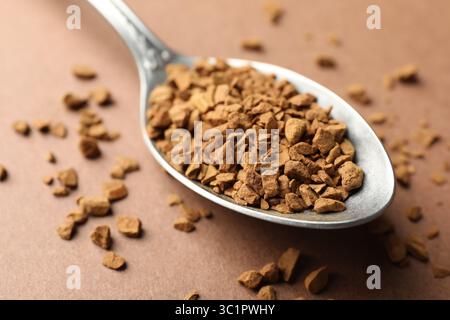 Cuillère avec café instantané granulé sur fond beige, gros plan Banque D'Images