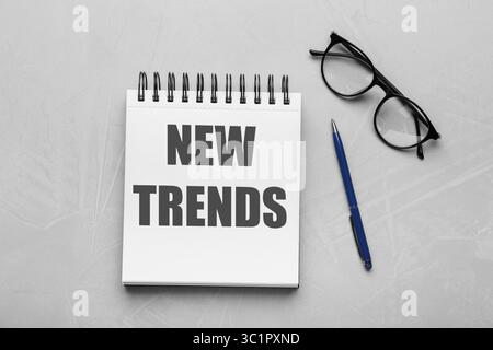 Nouvelles tendances inscription dans le carnet, lunettes et stylo sur fond rouge, vue de dessus Banque D'Images