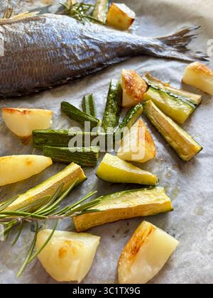 Poisson cuit au four avec des légumes comme les pommes de terre et les courgettes, les herbes, juste du four prêt à manger. Directement au-dessus. Banque D'Images