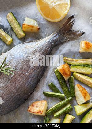 Poisson cuit au four avec des légumes comme les pommes de terre et les courgettes, les herbes, juste du four prêt à manger. Directement au-dessus. Banque D'Images